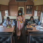 
              From left, Sibonino Nene, head of vaccination program, Ntombekhaya Kondile, data capturer, and Transvaco Manager Dr. Paballo Mowana have lunch aboard the COVID-19 vaccination train parked at the Swartkops railroad yard outside Gqeberha, South Africa, Thursday Sept. 23, 2021. South Africa has sent a train carrying COVID-19 vaccines into one of its poorest provinces to get doses to areas where healthcare facilities are stretched. The vaccine train, named Transvaco, will go on a three-month tour through the Eastern Cape province and stop at seven stations for two weeks at a time to vaccinate people. (AP Photo/Jerome Delay)
            