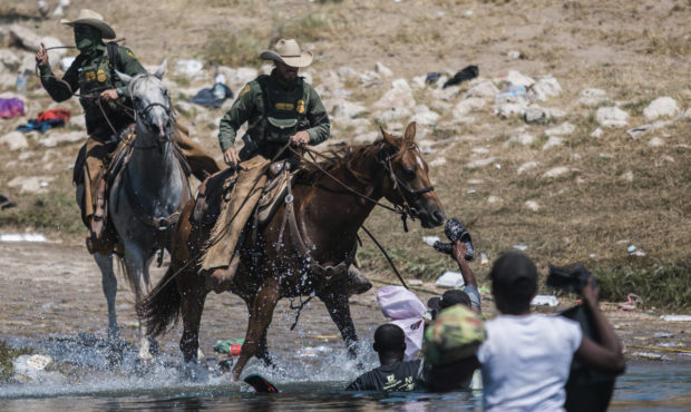 U.S. Customs and Border Protection mounted officers attempt to contain migrants as they cross the R...