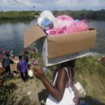 
              Haitian migrants carry provisions as they use a dam to cross into the United States from Mexico, Saturday, Sept. 18, 2021, in Del Rio, Texas. The Biden administration plans the widescale expulsion of Haitian migrants from the small Texas border city by putting them on on flights to Haiti starting Sunday, an official said Friday, representing a swift and dramatic response to thousands who suddenly crossed the border from Mexico and gathered under and around a bridge.  (AP Photo/Eric Gay)
            