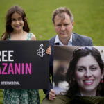
              Richard Ratcliffe, the husband of imprisoned British-Iranian Nazanin Zaghari-Ratcliffe and their seven year old daughter Gabriella pose for the media backdropped by the scaffolded Houses of Parliament and the Elizabeth Tower, known as Big Ben, in Parliament Square, London, to mark the 2,000 days she has been detained in Iran, Thursday, Sept. 23, 2021. Zaghari-Ratcliffe was originally sentenced to five years in prison after being convicted of plotting the overthrow of Iran's government, a charge that she, her supporters and rights groups deny. While employed at the Thomson Reuters Foundation, the charitable arm of the news agency, she was taken into custody at the Tehran airport in April 2016 as she was returning home to Britain after visiting family. (AP Photo/Matt Dunham)
            