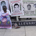 
              A relative of one of the 43 missing university students holds a placard with s photo of his loved one, as he joins others in a march on the seventh anniversary of their disappearance, in Mexico City, Sunday, Sept. 26, 2021. Relatives continue to demand justice for the Ayotzinapa students who were allegedly taken from the buses by the local police and handed over to a gang of drug traffickers. (AP Photo/Marco Ugarte)
            