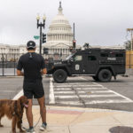 
              A runner pauses to allow an armored police vehicle to pass ahead of a rally near the U.S. Capitol in Washington, Saturday, Sept. 18, 2021. The rally was planned by allies of former President Donald Trump and aimed at supporting the so-called "political prisoners" of the Jan. 6 insurrection at the U.S. Capitol. (AP Photo/Nathan Howard)
            