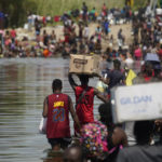 
              Haitian migrants use a dam to cross into and from the United States from Mexico, Saturday, Sept. 18, 2021, in Del Rio, Texas. The U.S. plans to speed up its efforts to expel Haitian migrants on flights to their Caribbean homeland, officials said Saturday as agents poured into a Texas border city where thousands of Haitians have gathered after suddenly crossing into the U.S. from Mexico. (AP Photo/Eric Gay)
            