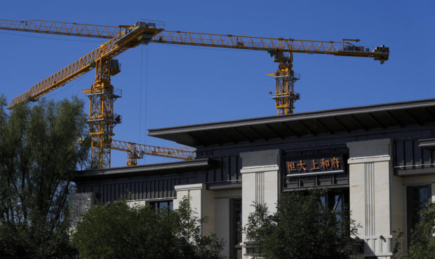 Construction cranes stand near an Evergrande new housing development showroom office building in Be...