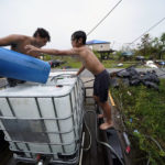 
              Terren Dardar, 17, left, and Dayton Verdin, 14, pour barrels of rainwater they collected from Tropical Storm Nicholas, in the aftermath of Hurricane Ida in Pointe-aux-Chenes, La., Tuesday, Sept. 14, 2021. They have had no running water since the hurricane, and collected 140 gallons of rainwater in two hours from the tropical storm, which they filter and pump into their house for showers. (AP Photo/Gerald Herbert)
            