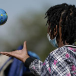 
              A Haitian migrant girl plays with a ball in the shape of a globe while waiting to board a bus to Houston provided by a humanitarian group after she and her family were released from U.S. Customs and Border Protection custody, Friday, Sept. 24, 2021, in Del Rio, Texas. (AP Photo/Julio Cortez)
            