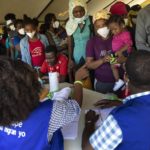 
              Haitians who were deported from the U.S. border with Mexico are attended by members of the IOM UN Migration organization before they get tested for COVID-19 at Toussaint Louverture International Airport in Port-au-Prince, Haiti, Monday, Sept. 20, 2021. The U.S. is flying Haitians camped in a Texas border town back to their homeland. (AP Photo/Rodrigo Abd)
            