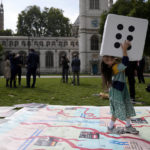 
              Gabriella, the seven year old daughter of imprisoned British-Iranian Nazanin Zaghari-Ratcliffe, joins in a game on a giant snakes and ladders board in Parliament Square, London, to show the "ups and downs" of Zaghari-Ratcliffe's case to mark the 2,000 days she has been detained in Iran, Thursday, Sept. 23, 2021. Zaghari-Ratcliffe was originally sentenced to five years in prison after being convicted of plotting the overthrow of Iran's government, a charge that she, her supporters and rights groups deny. While employed at the Thomson Reuters Foundation, the charitable arm of the news agency, she was taken into custody at the Tehran airport in April 2016 as she was returning home to Britain after visiting family. (AP Photo/Matt Dunham)
            