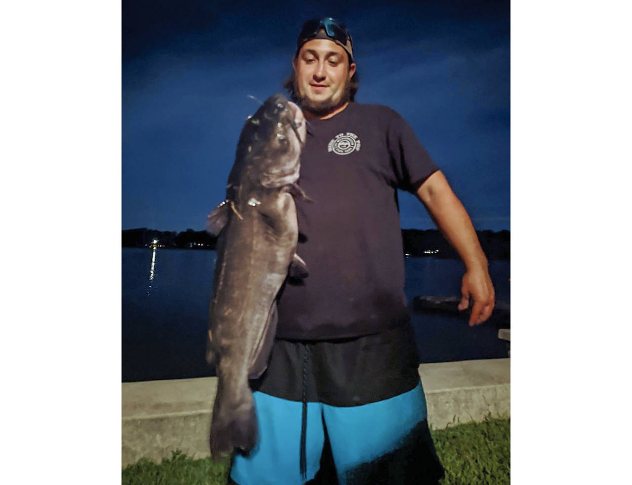 FILE - This Aug. 21, 2021, file photo provided by Chris Braga, shows Ben Tomkunas holding a catfish...