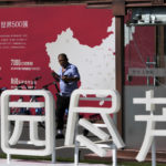 
              A security guard walks by a map showing Evergrande development projects in China at an Evergrande new housing development in Beijing, Wednesday, Sept. 22, 2021. The Chinese real estate developer whose struggle to avoid defaulting on billions of dollars of debt has rattled global markets announced Wednesday it will make a closely watched interest payment due this week, while the government was silent on whether it might intervene. (AP Photo/Andy Wong)
            