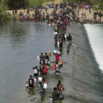 
              Haitian migrants use a dam to cross into and from the United States from Mexico, Saturday, Sept. 18, 2021, in Del Rio, Texas. The U.S. plans to speed up its efforts to expel Haitian migrants on flights to their Caribbean homeland, officials said Saturday as agents poured into a Texas border city where thousands of Haitians have gathered after suddenly crossing into the U.S. from Mexico. (AP Photo/Eric Gay)
            