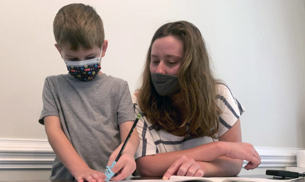 Emily Goss goes over school work at the kitchen table with her five-year-old son inside their Monro...