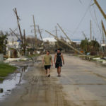 
              People walk through a neighborhood damaged by Hurricane Ida, Monday, Sept. 6, 2021, in Grand Isle, La. (AP Photo/John Locher)
            