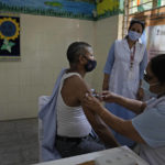 
              A health worker administers the vaccine for COVID-19 at a vaccination center set up at a government-run school in New Delhi, India, Tuesday, Sept. 21, 2021. India, the world's largest vaccine producer, will resume exports and donations of surplus coronavirus vaccines in October after halting them during a devastating surge in domestic infections in April, the health minister said Monday. (AP Photo/Manish Swarup)
            