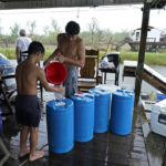 
              Terren Dardar, 17, and Dayton Verdin, 14, left, pour barrels of rainwater they collected from Tropical Storm Nicholas, in the aftermath of Hurricane Ida in Pointe-aux-Chenes, La., Tuesday, Sept. 14, 2021. They have had no running water since the hurricane, and collected 140 gallons of rainwater in two hours from the tropical storm, which they filter and pump into their house for showers. (AP Photo/Gerald Herbert)
            