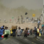 
              A dust storm moves across the area as Haitian migrants use a dam to cross into and from the United States from Mexico, Saturday, Sept. 18, 2021, in Del Rio, Texas. The U.S. plans to speed up its efforts to expel Haitian migrants on flights to their Caribbean homeland, officials said Saturday as agents poured into a Texas border city where thousands of Haitians have gathered after suddenly crossing into the U.S. from Mexico. (AP Photo/Eric Gay)
            