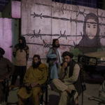 
              Taliban members sit in front of a mural depicting a woman behind barbed wire in Kabul, Afghanistan, Tuesday, Sept. 21, 2021. (AP Photo/Felipe Dana)
            