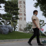 
              A cleaner walks by the Evergrande's name and logo at its new housing development in Beijing, Wednesday, Sept. 15, 2021. One of China's biggest real estate developers is struggling to avoid defaulting on billions of dollars of debt, prompting concern about the broader economic impact and protests by apartment buyers about delays in completing projects. Rating agencies say Evergrande Group appears likely to be unable to repay all of the 572 billion yuan ($89 billion) it owes banks and other bondholders. That might jolt financial markets, but analysts say Beijing is likely to step in to prevent wider damage. (AP Photo/Andy Wong)
            