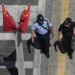 
              A policeman, right, and security guard walk past Chinese flags outside the Evergrande headquarters in Shenzhen, China, Friday, Sept. 24, 2021. Things appeared quiet at the headquarters of the heavily indebted Chinese real estate developer Evergrande, one day after the day it had promised to pay interest due to bondholders in China. (AP Photo/Ng Han Guan)
            