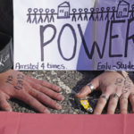 
              A view of the hands of protesters from Insulate Britain stuck to the ground as they block the A20 which provides access to the Port of Dover, in Kent, England, Friday, Sept. 24, 2021. The environmental activists have moved location after been banned from campaigning on the M25 motorway in London. (Gareth Fuller/PA via AP)
            