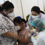
              A mother comforts her child receiving the Pfizer-BioNTech COVID-19 vaccine at a hospital in Bangkok, Thailand, Tuesday, Sept. 21, 2021. Bangkok Metropolitan Administration inoculated 12-18 year old students Tuesday as part of its attempt to reopen on-site schools. (AP Photo/Sakchai Lalit)
            