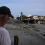 
              Kelty Readenour stands on his porch overlooking a sand and debris-covered roadway and homes destroyed by Hurricane Ida, Monday, Sept. 6, 2021, in Grand Isle, La. (AP Photo/John Locher)
            