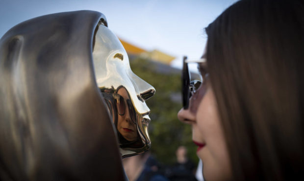 A woman looks at her reflection in a newly unveiled statue of the mysterious developer of the Bitco...
