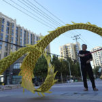 
              A resident twirls a cloth dragon outside the Evergrande Yujing Bay residential complex in Beijing, China, Tuesday, Sept. 21, 2021. Global investors are watching nervously as one of China's biggest real estate developers struggles to avoid defaulting on tens of billions of dollars of debt, fueling fears of possible wider shock waves for the financial system. (AP Photo/Ng Han Guan)
            