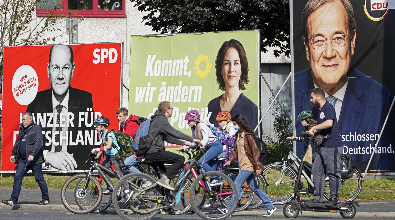People walk and drive past election posters of the three chancellor candidates, from right, Armin L...