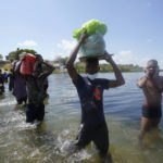 
              Haitian migrants use a dam to cross into and from the United States from Mexico, Saturday, Sept. 18, 2021, in Del Rio, Texas. The U.S. plans to speed up its efforts to expel Haitian migrants on flights to their Caribbean homeland, officials said Saturday as agents poured into a Texas border city where thousands of Haitians have gathered after suddenly crossing into the U.S. from Mexico. (AP Photo/Eric Gay)
            