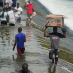 
              Haitian migrants carry provisions as they use a dam to cross into and from the United States from Mexico, Saturday, Sept. 18, 2021, in Del Rio, Texas. The U.S. plans to speed up its efforts to expel Haitian migrants on flights to their Caribbean homeland, officials said Saturday as agents poured into a Texas border city where thousands of Haitians have gathered after suddenly crossing into the U.S. from Mexico. (AP Photo/Eric Gay)
            