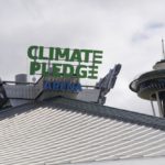 The roof-top sign for Climate Pledge Arena is shown next to the Space Needle, Wednesday, Oct. 20, 2021, ahead of the NHL hockey Seattle Kraken's home opener Saturday against the Vancouver Canucks in Seattle. The historic angled roof of the former KeyArena was preserved, but everything else inside the venue, which will also host concerts and be the home of the WNBA Seattle Storm basketball team, is brand new. (AP Photo/Ted S. Warren)