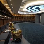 A worker puts the final touches on woodwork in the Seattle Kraken's locker room at Climate Pledge Arena, Wednesday, Oct. 20, 2021, during a media tour ahead of the NHL hockey team's home opener Saturday against the Vancouver Canucks in Seattle. The historic angled roof of the former KeyArena was preserved, but everything else inside the venue, which will also host concerts and be the home of the WNBA Seattle Storm basketball team, is brand new. (AP Photo/Ted S. Warren)