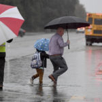 
              As the rain falls, a father walks his son to Garfield Elementary through a flooded section of Peach and Need Avenues, on Monday, Oct. 25, 2021, in Clovis, Calif. A massive storm barreled toward Southern California on Monday after flooding highways, toppling trees, cutting power to about 380,000 utility customers and causing rock slides and mud flows in areas burned bare by wildfires across the northern half of the state. (John Walker/The Fresno Bee via AP)
            