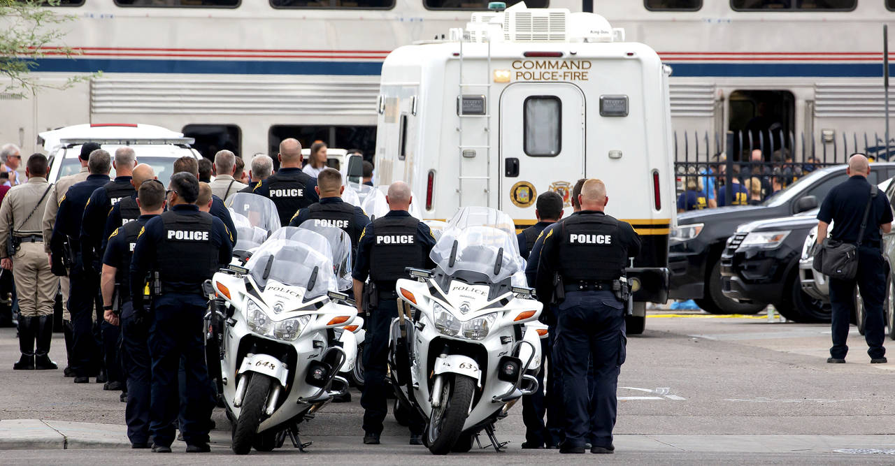 Tucson Police officers and other law enforcement officers stand at attention as the body of a Drug ...