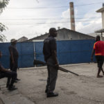 
              Armed private security guards stand watch at the main entrance of the Shodecosa industrial park, in Port-au-Prince, Haiti, Tuesday, Sept. 28, 2021. Shodecosa is Haiti's largest industrial park, which warehouses most of the 93 percent of the nation's food that is imported. (AP Photo/Rodrigo Abd)
            