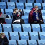 
              Team personnel wearing face masks to protect against COVID-19 watch the action at the ISU World Cup Short Track speed skating competition, a test event for the 2022 Winter Olympics, at the Capital Indoor Stadium in Beijing, Friday, Oct. 22, 2021. (AP Photo/Mark Schiefelbein)
            