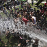 
              Migrants who have been marching in a caravan heading north enjoy water sprayed from a hose, in Huehuetan, in the state of Chiapas, Mexico, Sunday, Oct. 24, 2021. Migrant-rights advocates and aid workers travelling with the caravan estimate there could be 1,000 children among the estimated 4,000 people trudging along the highways under a punishing sun. (AP Photo/Marco Ugarte)
            