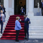 
              German Chancellor Angela Merkel, speaks Greece's Prime Minister Kyriakos Mitsotakis, as she leaves the Maximos Mansion, at the end of their meeting in Athens, Greece, Friday, Oct. 29, 2021. Germany's outgoing Chancellor Angela Merkel is on a two-day visit to the country whose financial crisis marked much of her tenure and Germany's relationship with Europe. (AP Photo/Thanassis Stavrakis)
            