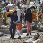 
              A family brings flowers to the Valle de Chalco municipal cemetery as people begin to arrive to pay their respects to their dead, on the outskirts of Mexico City, Sunday, Oct. 31. 2021. (AP Photo/Marco Ugarte)
            