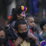 
              A child dressed as a "Catrina" is carried on the shoulders of a relative during Day of the Dead festivities in Mexico City, Sunday, Oct. 31, 2021. Altars and artwork from around the country were on display in a parade, as Mexicans honor the Day of the Dead. (AP Photo/Fernando Llano)
            
