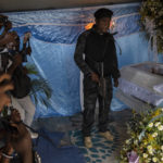 
              Jimmy Cherizier, aka Barbecue, a former policeman who leads the G9 gang coalition, holds a weapon as he stands next to the coffin that contain the remains of Tonino Manino, one of his lieutenants, during a funeral service in Port-au-Prince, Haiti, Thursday, Sept. 30, 2021. Barbecue has been accused -- by local and national courts and the United Nations and other international organizations -- of participation in three massacres between 2018 and 2020. There is a warrant for his arrest, although he's "hiding" in plain sight, protected by gunmen. (AP Photo/Rodrigo Abd)
            