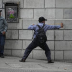 
              A protester aims a slingshot at police during a protest of veterans demanding that a law be passed that compensates them for having served during the country's civil war, outside the Congress building in Guatemala City, Tuesday, Oct. 19, 2021. (AP Photo/Moises Castillo)
            