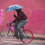 
              A man attempts to stay dry while riding along Colorado Boulevard in Pasadena, Calif., during a rainstorm, Monday, Oct. 25, 2021. (Sarah Reingewirtz/The Orange County Register via AP)
            