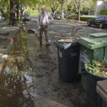 
              Robert Schmidt cleans up after Saturday's storm in front of his home on C Street in San Rafael, Calif., on Monday, Oct. 25, 2021. During the storm, the street was under water, with several inches of water entering Schmidt's garage. (Alan Dep/Marin Independent Journal via AP)
            
