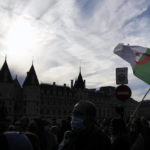 
              A demonstrator holds an Algerian flag during a march in Paris, Sunday, Oct. 17, 2021. A tribute march was organized for the 60th anniversary of the bloody police crackdown on a protest by Algerians in the French capital, during the final year of their country's independence war with its colonial power. (AP Photo/Christophe Ena)
            