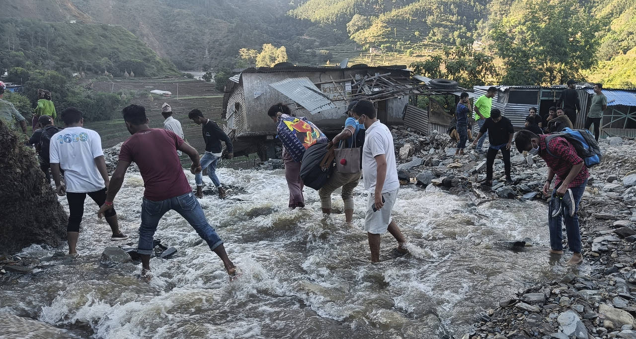 People wade past a flooded area in Dipayal Silgadhi, Nepal, Thursday, Oct. 21, 2021. Floods and lan...