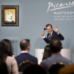 Oliver Barker, auctioneer and chairman of Sotheby's Europe, declares the sale of Pablo Picasso's "Femme au béret rouge-orange," displayed at left, during an auction at the Bellagio hotel and casino Saturday, Oct. 23, 2021, in Las Vegas. Sotheby's and the MGM Resorts Fine Art Collection hosted the auction, which raised $109 million from eleven pieces. (AP Photo/Ellen Schmidt)
