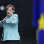 
              FILE - German Chancellor Angela Merkel stands behind a European flag as she waits for the arrival of Chinese President Xi Jinping at the chancellery in Berlin, Germany, July 5, 2017. Angela Merkel said in interview with weekly paper Frankfurter Allgemeine Zeitung, she is satisfied with the timing of her departure after 16 years at the helm of the country and was now looking forward to dedicate time to things she had to neglect during her chancellorship. (AP Photo/Markus Schreiber, File)
            