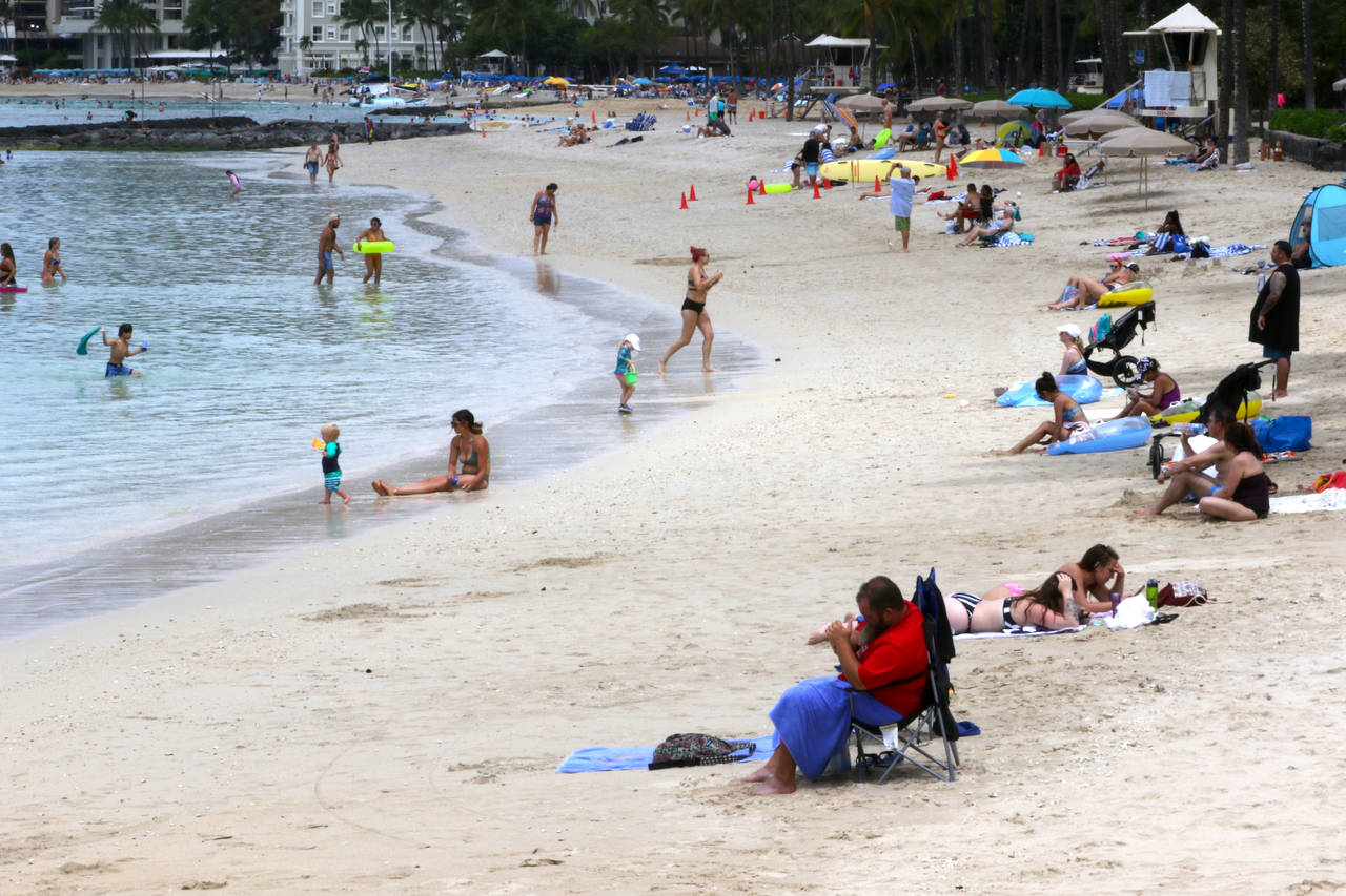 FILE — In this Aug. 24, 2021, file photo people sit on Waikiki Beach in Honolulu. Hawaii's COVID-...